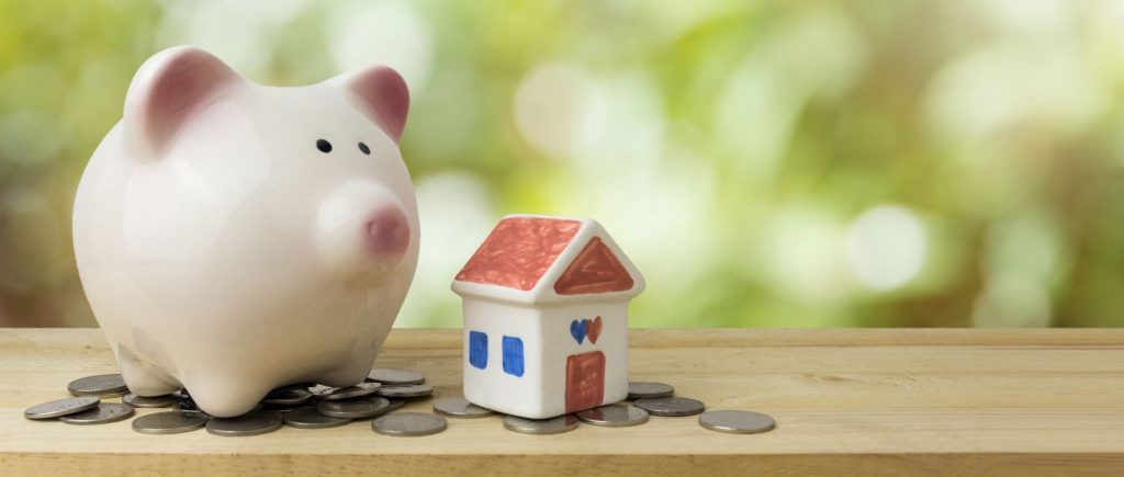 piggy bank next to a toy house and coins
