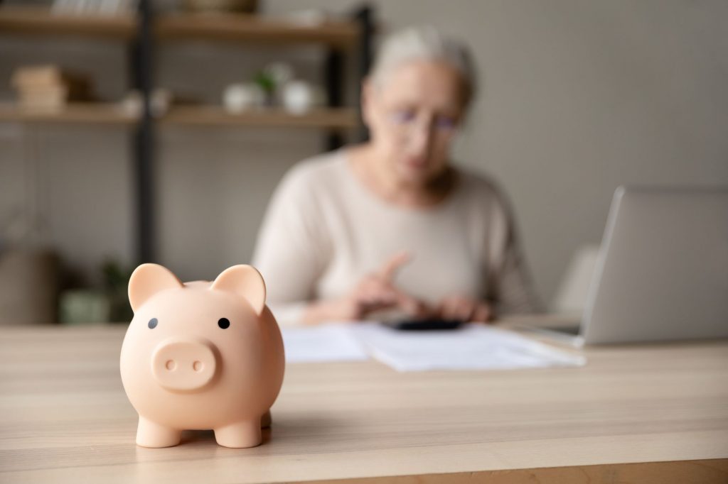 piggy bank with woman doing bills in background