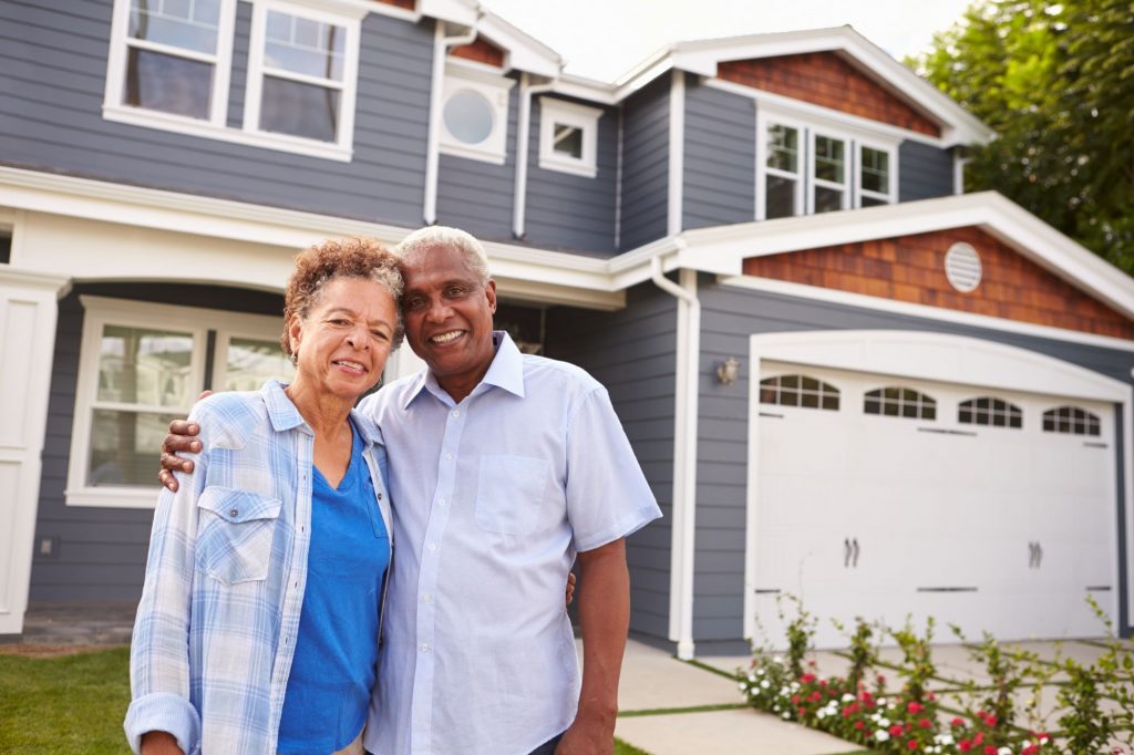 senior couple outside of house Is It Better To Buy Or Rent A Home For Retirement?