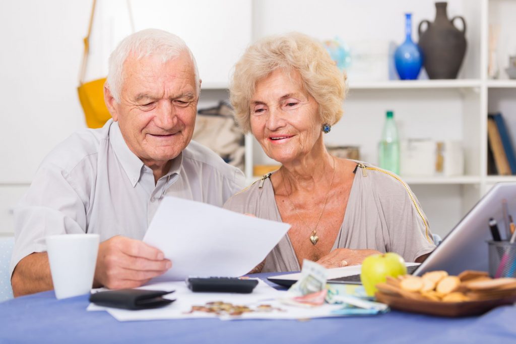 elderly couple calculating reverse mortgage at kitchen table