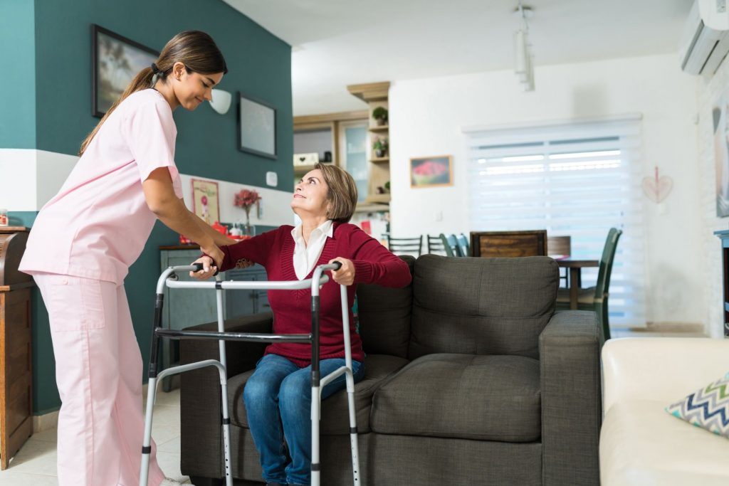in-home care provider Aide helping woman stand up with walker