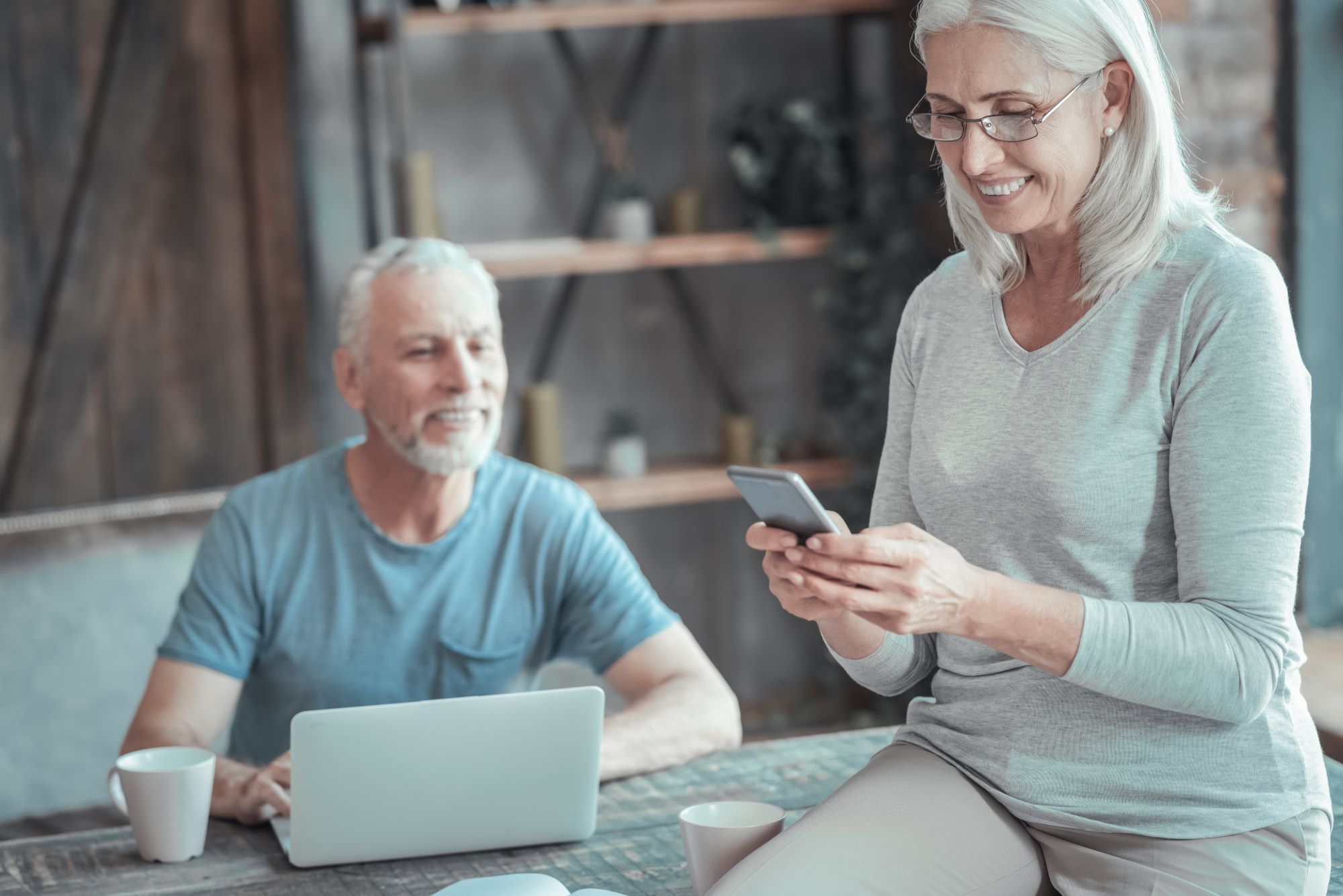 senior couple looking at phone and computer to calculate their social security benefits