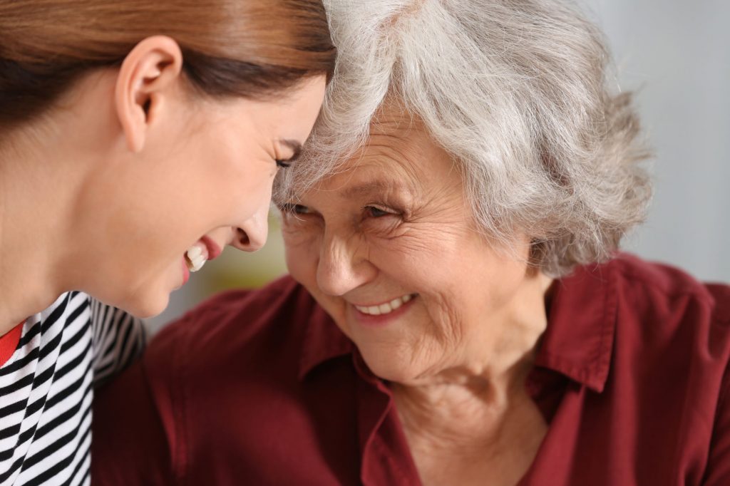 daughter and mom smiling at each other about aging in place safety tips for alzheimer's