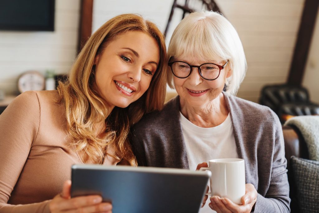woman and her senior mother looking at a tablet and smiling