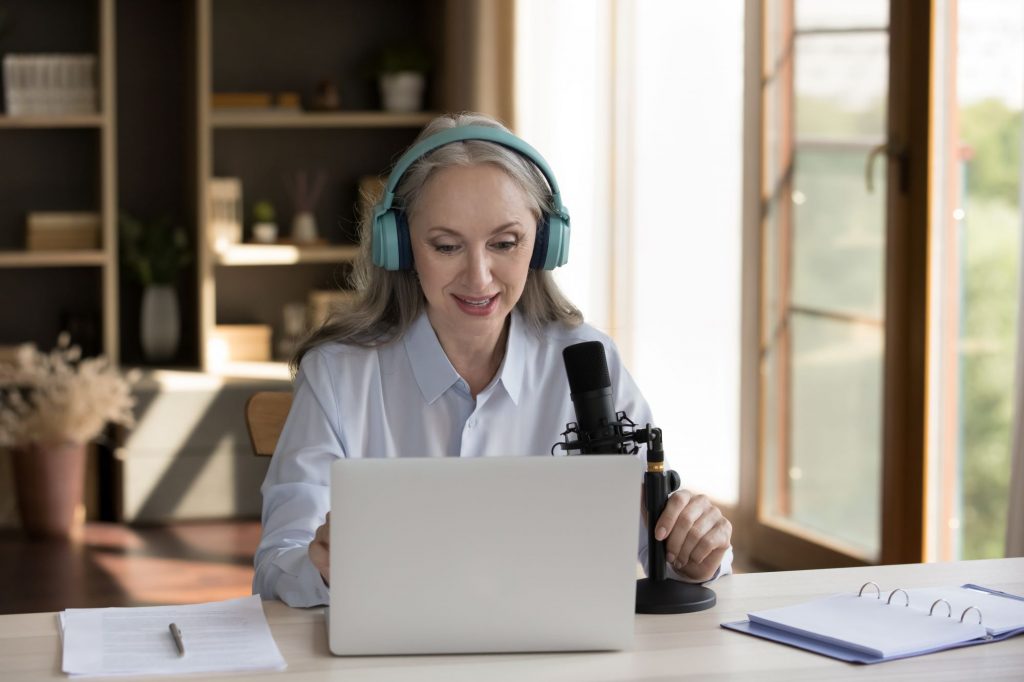 woman doing podcast with computer and headphones
