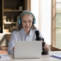 woman doing podcast with computer and headphones