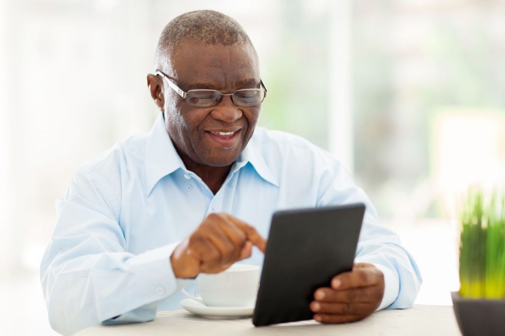 African American senior man using tablet to decide on changes during Medicare Annual Enrollment