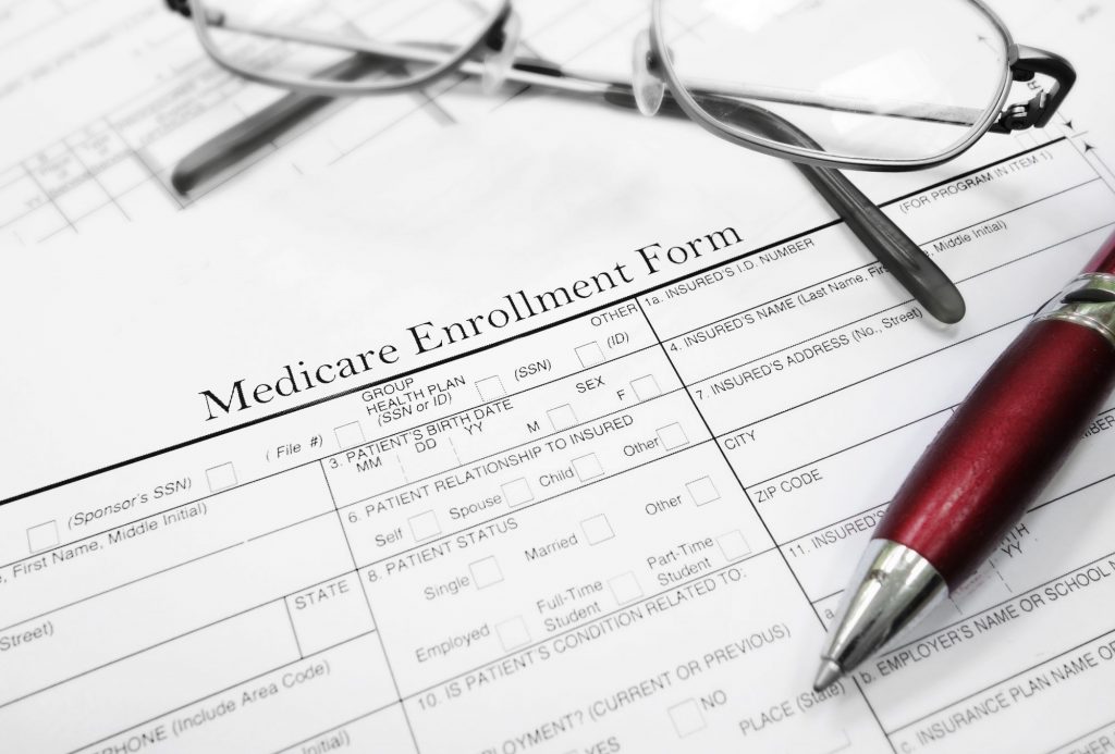 Medicare enrollment paper with glasses and pen