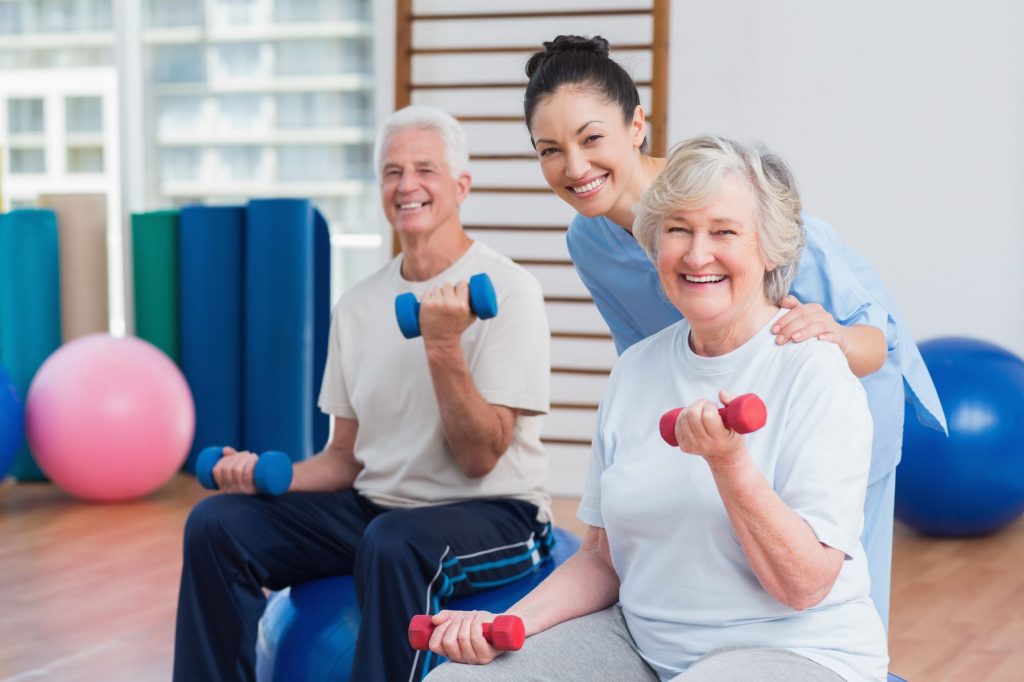 Happy seniors exercising with caregiver.