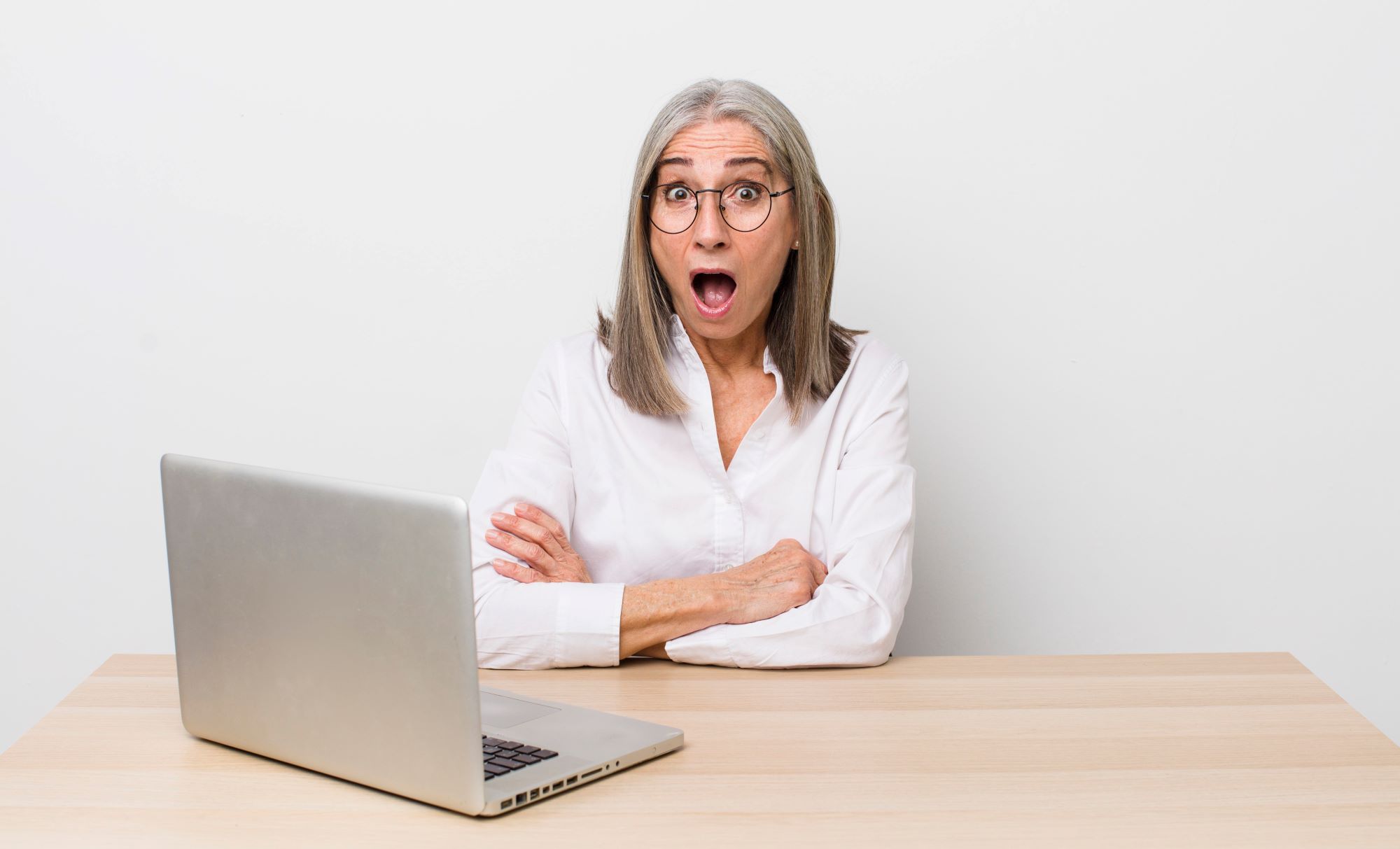 shocked 55+ woman sitting in front of an open computer