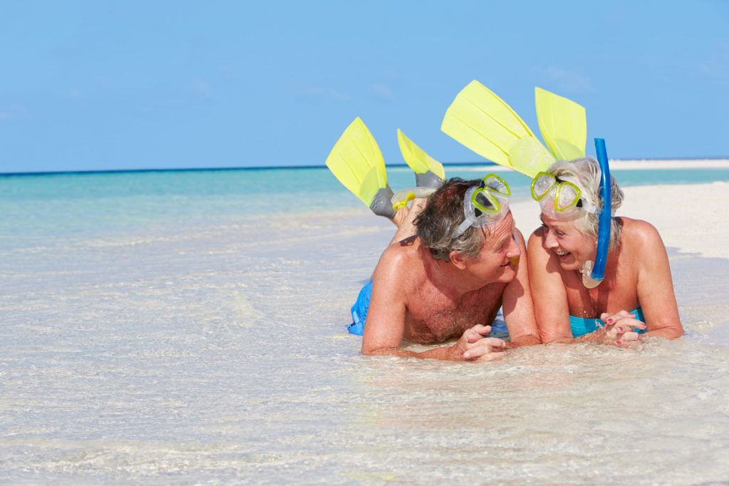 Medicare and Travel senior couple snorkeling on a trip