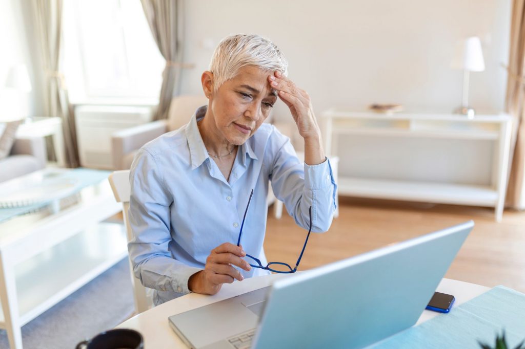senior woman sitting at a computer looking stressed