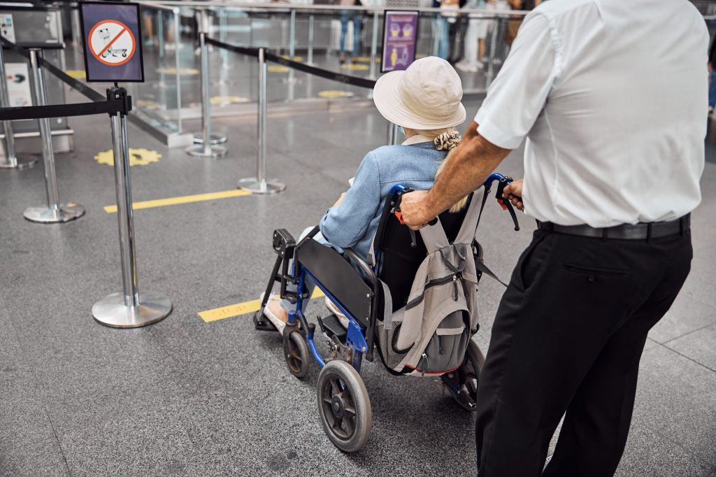 Companions for Older Travelers at the airport. Woman being pushed in a wheelchair through the airport