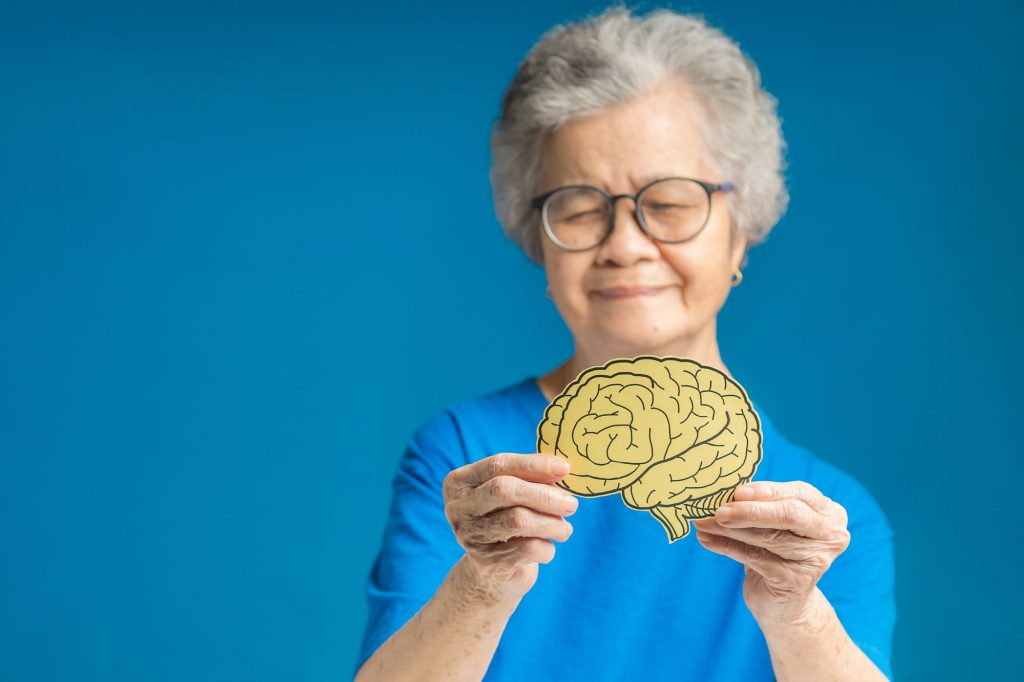 elderly woman holding a photo of a brain