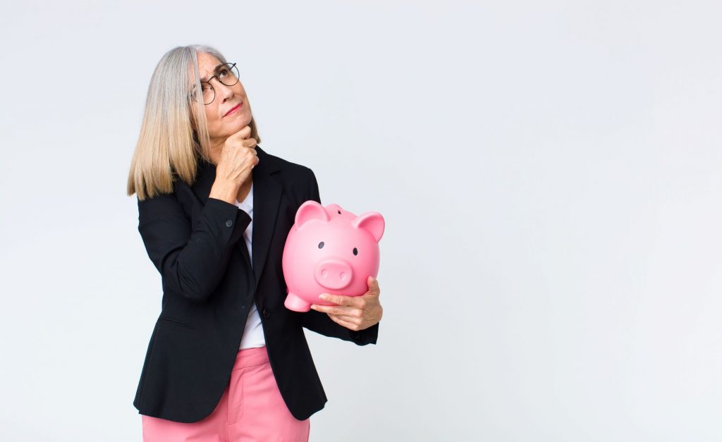 How Much WIll You Need to Save for Retirement? woman holding piggy bank and thinking
