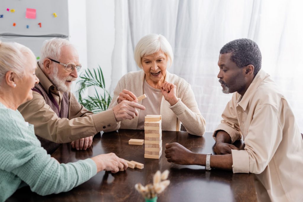 Multiethnic group of elderly friends playing a game of Jenga. 