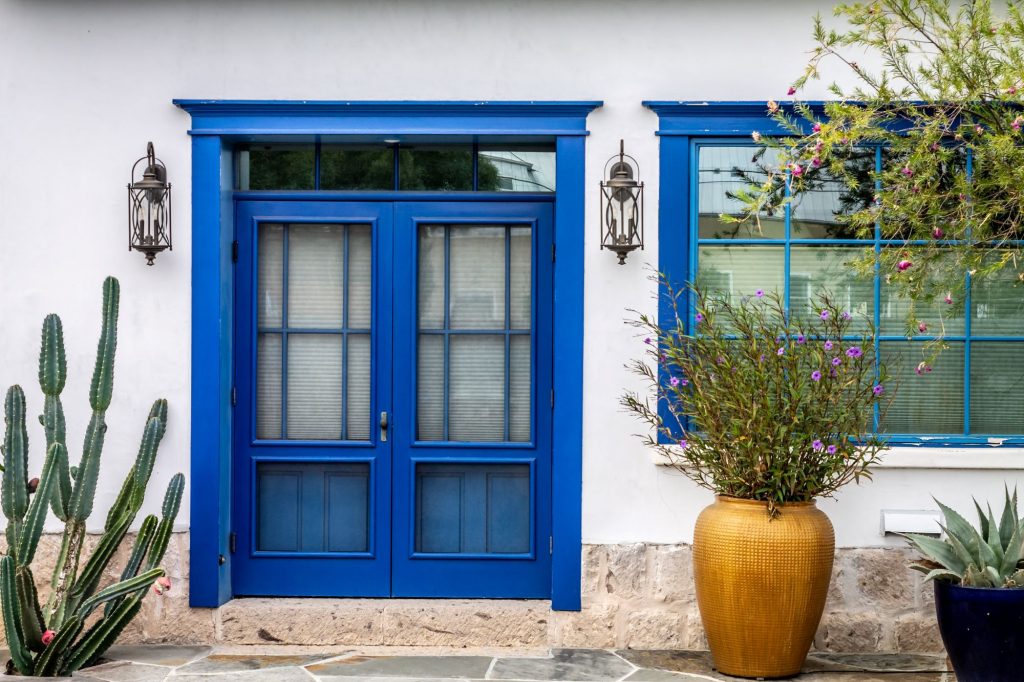 House with royal blue door and cacti and desert plants lining the front porch.