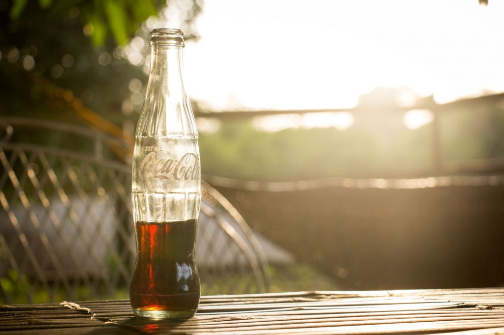 Remember when soda was called pop and came in a small bottle for only a dime?  Half-empy Coke bottle in the sun light.
