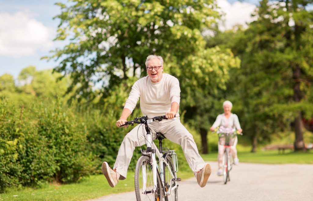 Elderly gentleman enjoying a bike ride in the countryside with his wife.