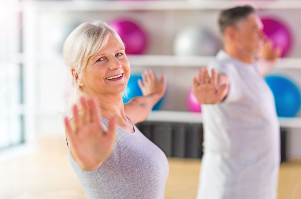 Older smiling lady taking an exercise class.