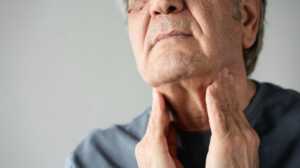 man examining own thyroid