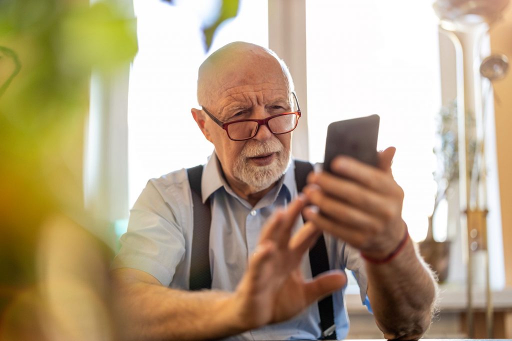 elderly man holding phone very confused