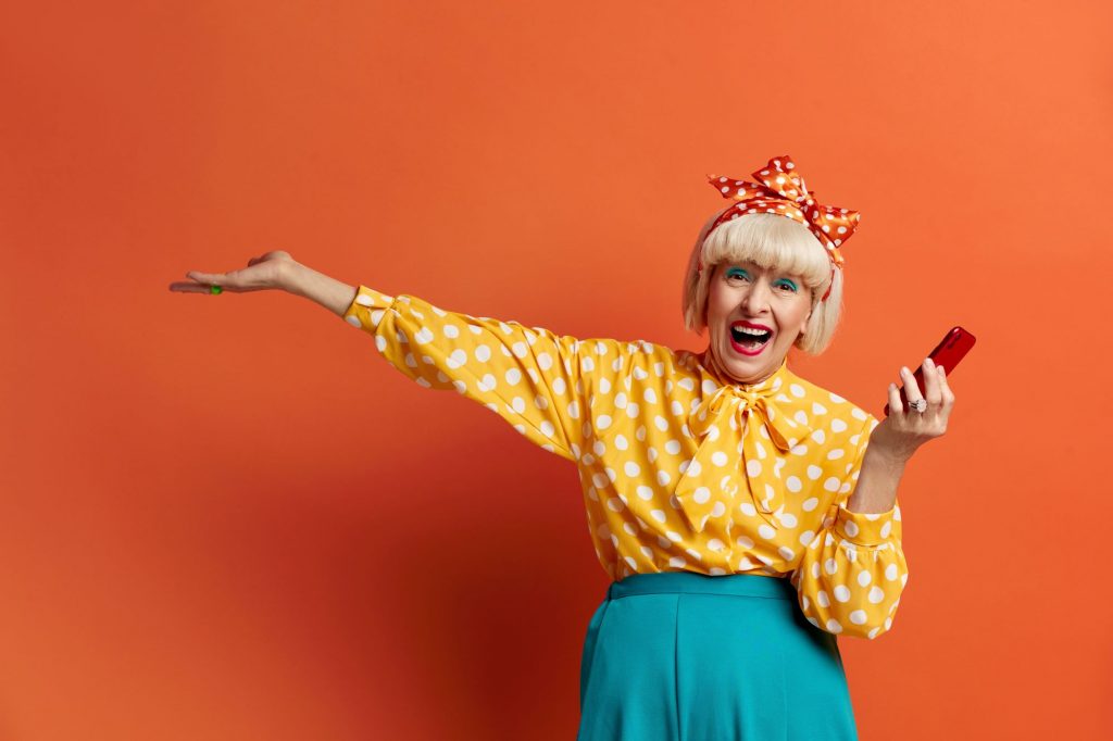 Boomer lady wearing yellow polka dot shirt holding a red phone 