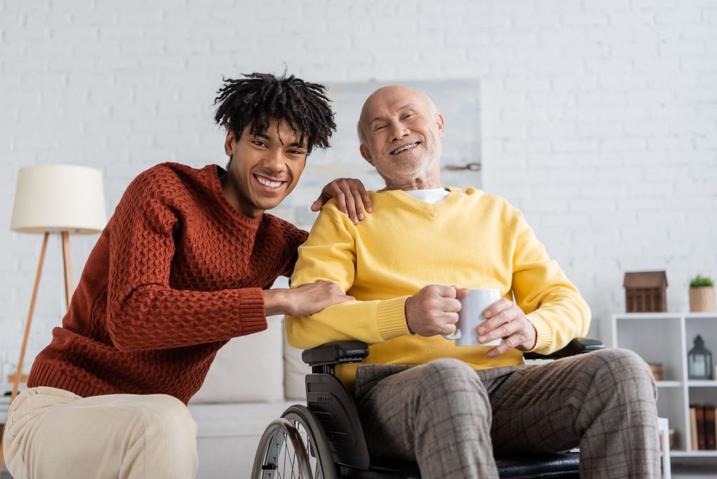 African American home caregiver and white senior in a wheelchair smiling