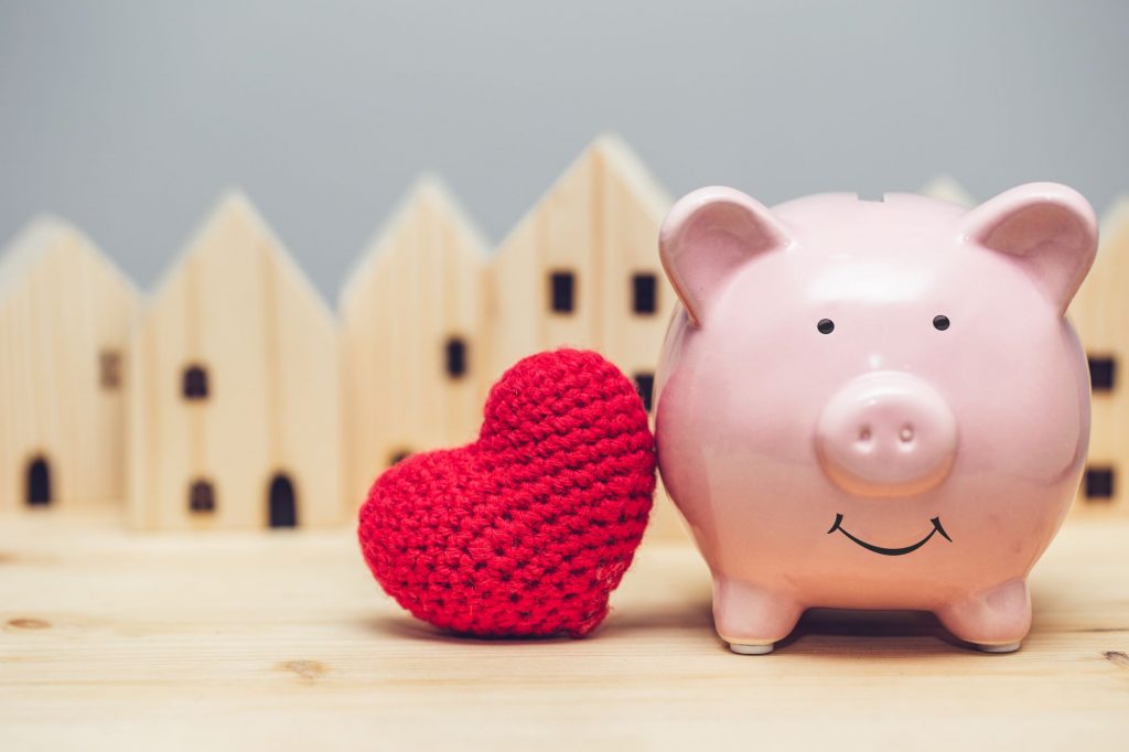 piggy bank with heart and houses in background