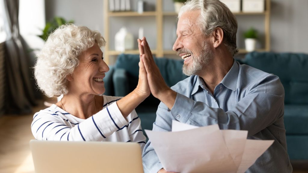 White Boomer couple high-fiving in their home.