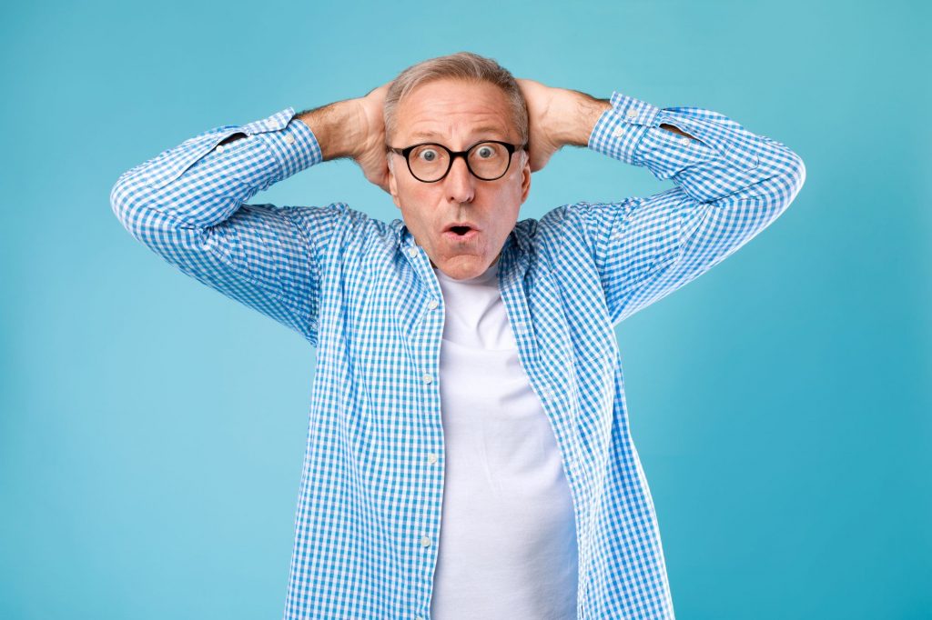 senior man in glasses with hands on his head - how to avoid Medicare scams