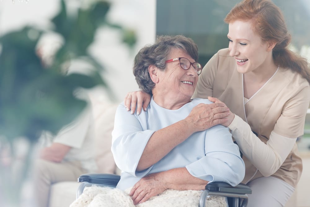 young woman helping older adult in assisted living facility