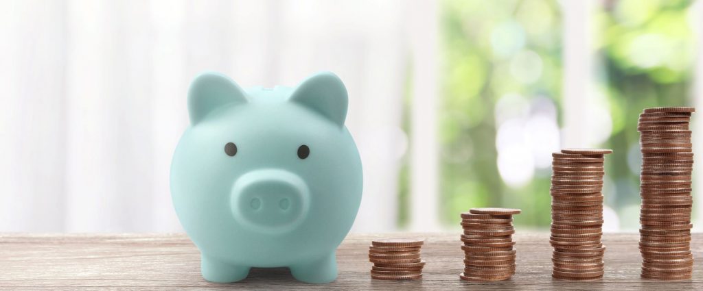 mint colored piggy bank next to stacked coins