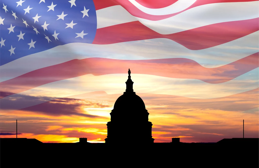 United States Capitol building silhouette and US flag against the sunset