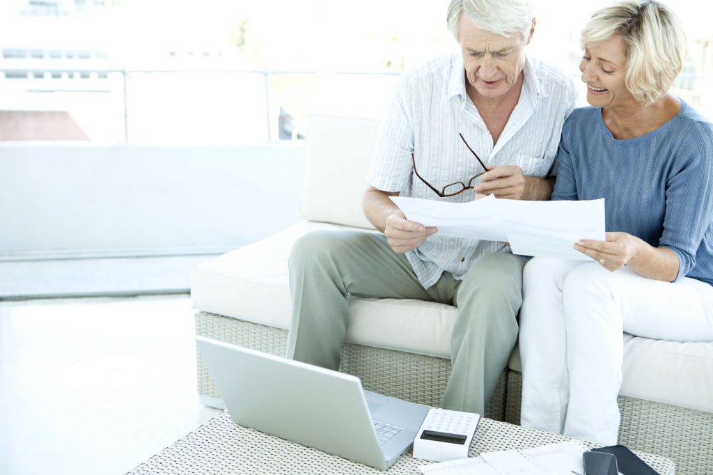 couple looking at papers and computer on couch