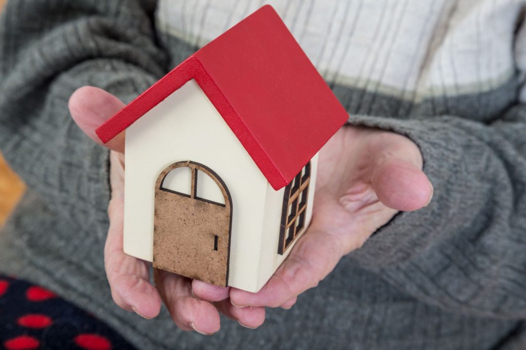 senior hands holding toy house to represent reverse mortgage