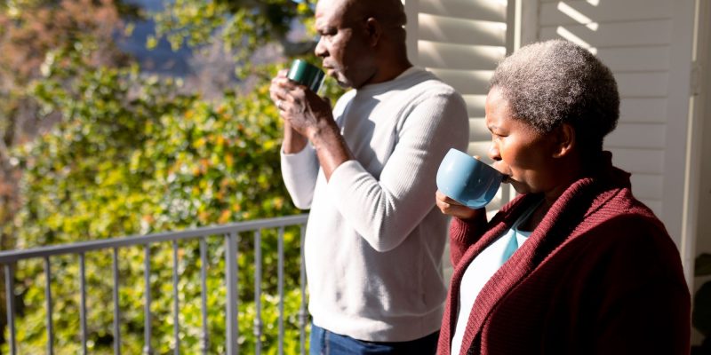 senior couple on apartment balcony drinking coffee