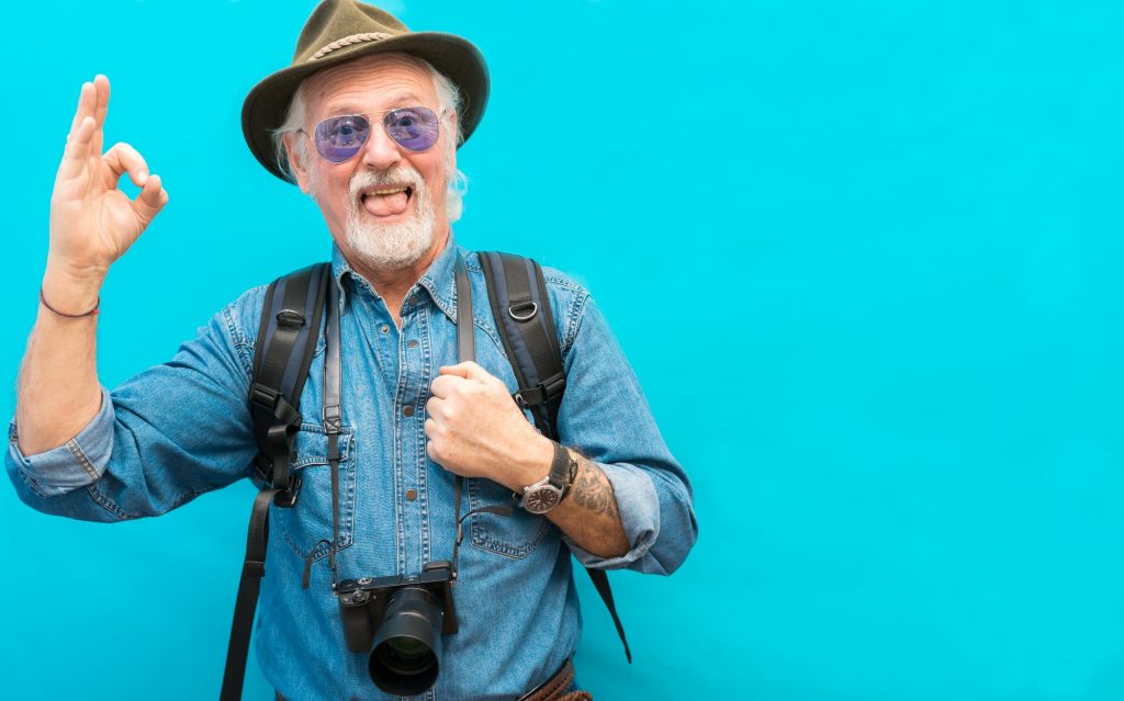 older adult male with white hair and beard dressed for travel