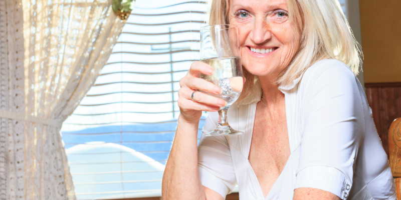 senior woman drinking water out of a fancy glass