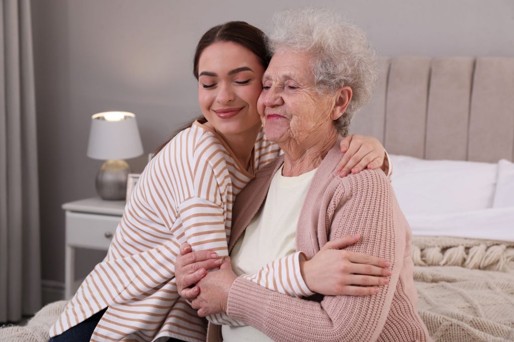 younger woman hugging senior woman with alzheimer's disease or another form of dementia