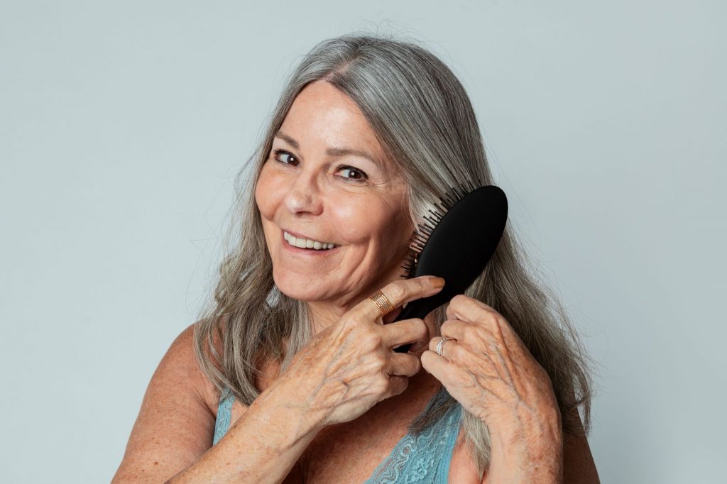 over 55 woman brushing her hair and smiling aging