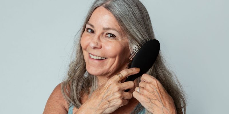 over 55 woman brushing her hair and smiling