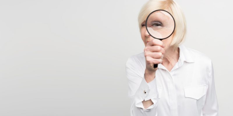 elderly woman holding a magnifying glass