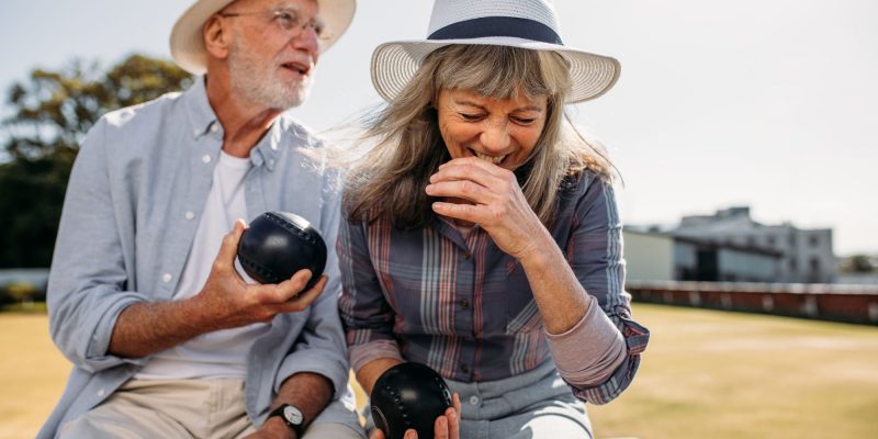 two seniors playing bocce ball and laughing