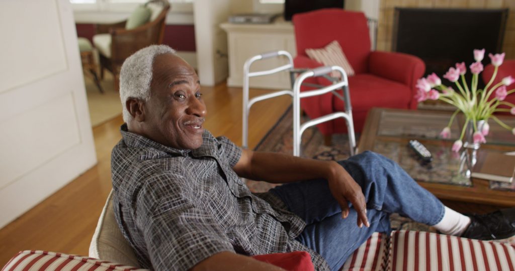 retiree sitting on couch smiling