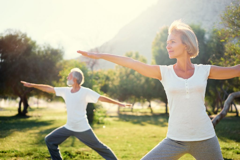 two 55+ adults balancing with yoga