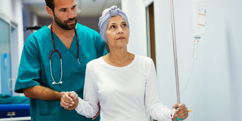 woman with cancer walking with nurse and IV