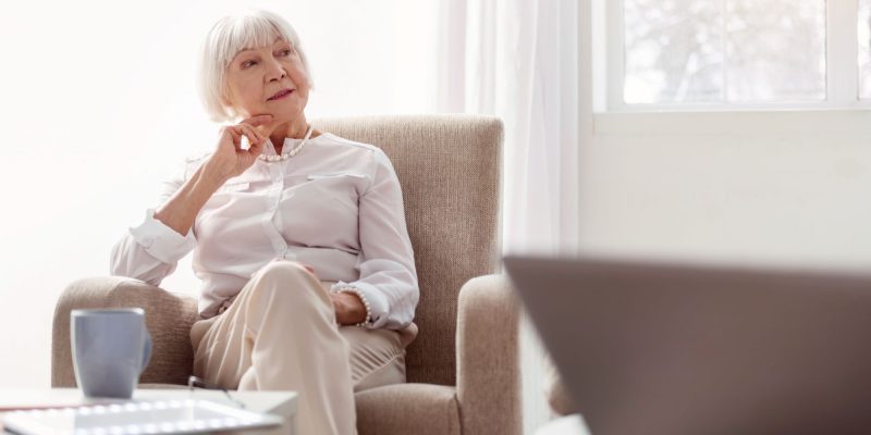 Senior Woman sitting in an armchair thinking