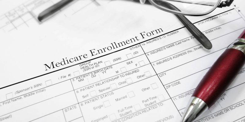 Medicare enrollment paper with glasses and pen