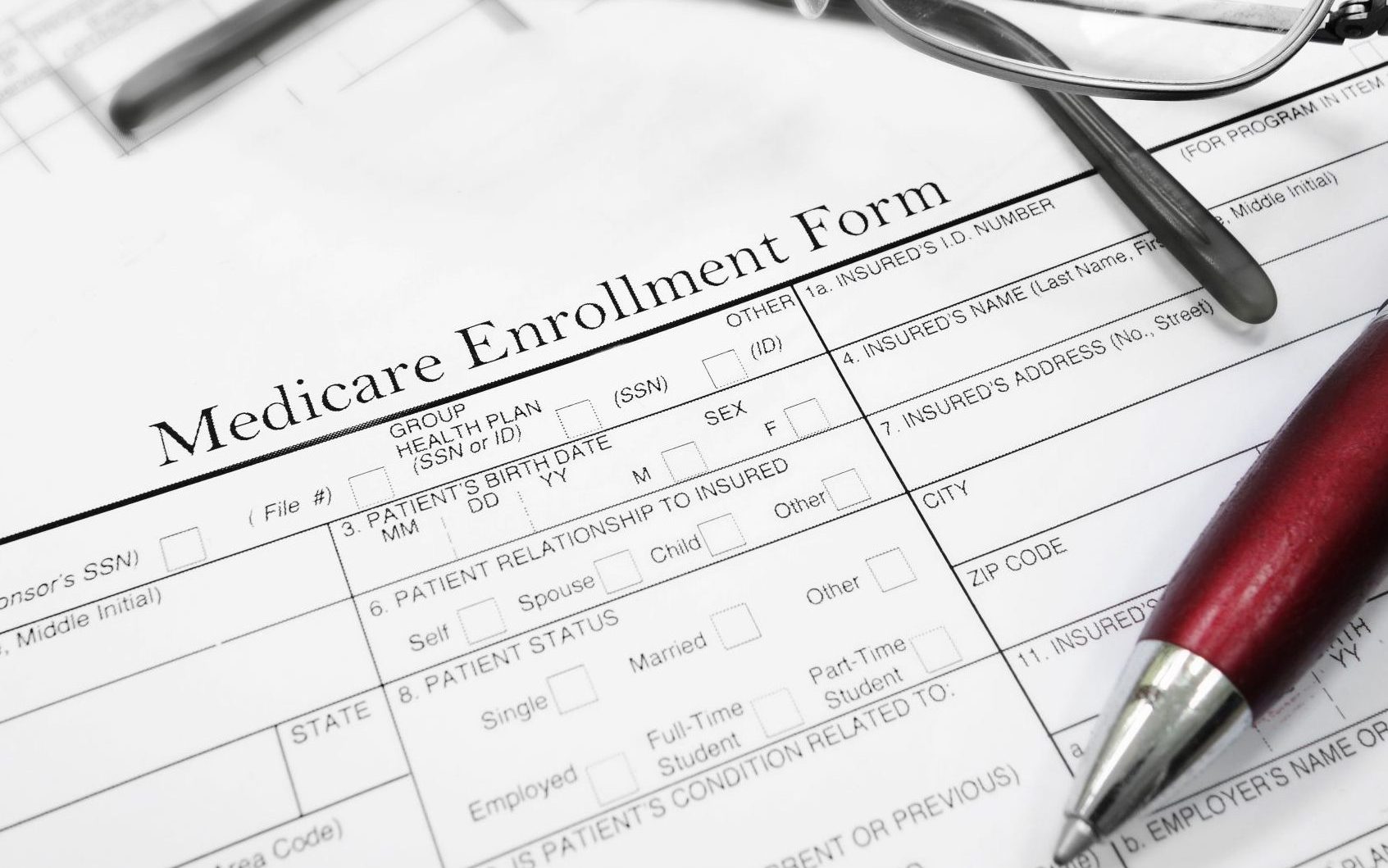 Medicare enrollment paper with glasses and pen